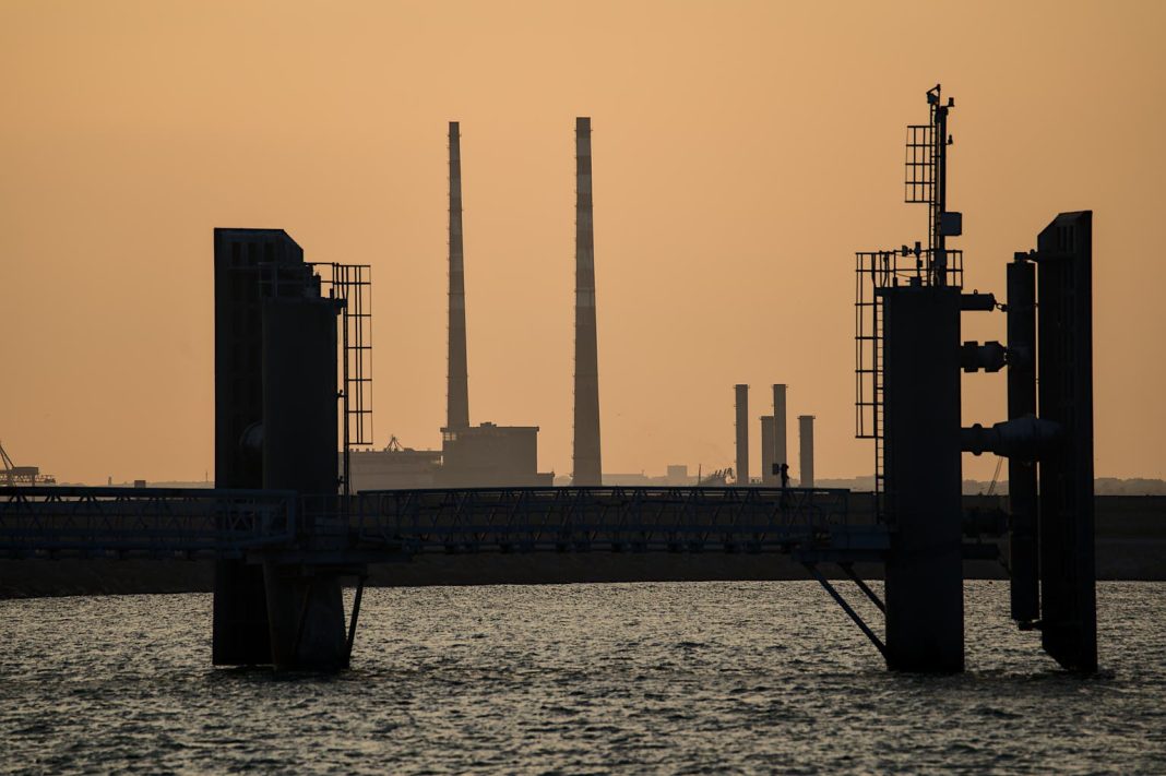 Telephoto view Poolbeg CCGT chimneys and Pigeon House Powers Station between wingwalls of St Michael pier ferry terminal in Dun Laoghaire harbor, Dublin, Ireland